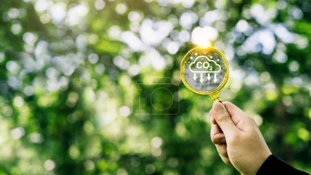 Hand holding magnifying glass with CO2 reduction icon inside. carbon credit to limit global warming from A climate-neutral long-term strategy greenhouse gas emissions targets.
