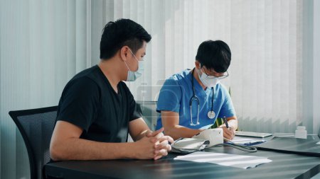 Téléchargez les photos : Médecin asiatique utilise le moniteur de pression artérielle d'un patient au moment de son bilan annuel et explique sa pression artérielle. - en image libre de droit