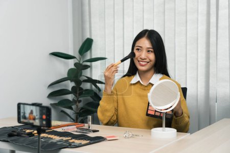 Téléchargez les photos : Jeune blogueur beauté asiatique présente des produits cosmétiques ainsi que des tutoriels sur la façon d'appliquer et d'enregistrer des tutoriels de maquillage sur les réseaux sociaux. - en image libre de droit