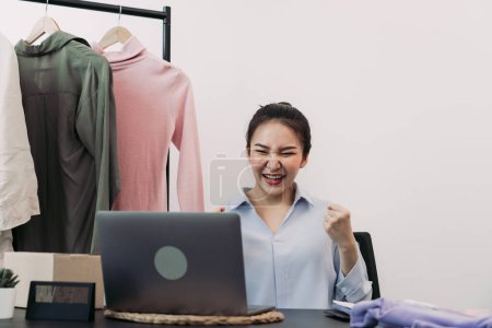 Téléchargez les photos : Les jeunes entrepreneurs asiatiques sont enthousiastes à l'idée d'atteindre l'objectif de vente de vêtements d'aujourd'hui. - en image libre de droit