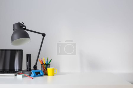 Photo for Office creative desk with lamp laptop  on wall background. Home office work space. - Royalty Free Image