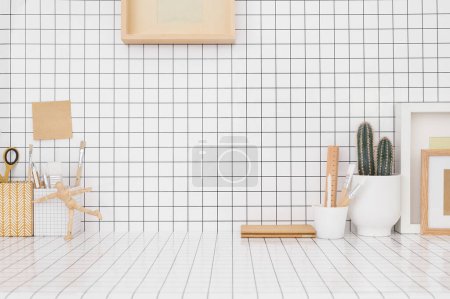 Photo for Desk at home on a checkered wall, wooden supplies, boxes, brushes. Young artists creative workspace. - Royalty Free Image