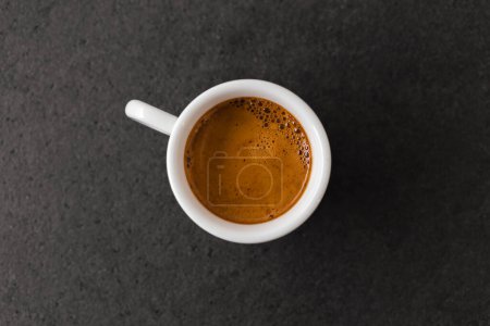 Photo for Cup of hot espresso coffee on dark table with brown beautiful crema. - Royalty Free Image