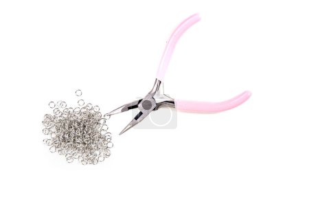 Small pink plastic handled beading pliers with a pile of jump rings