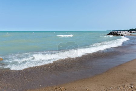 Lake Michigan lake superior, great lakes, petosky stones, clear bright blue water with a light blue sky, rocky beach. Rough waves.