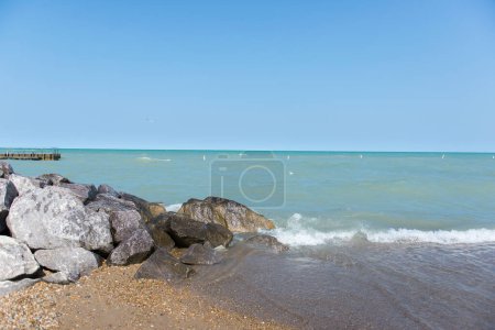 Beach near Lake Michigan. Rough waves. A pile of large stones near the lake and the beach.