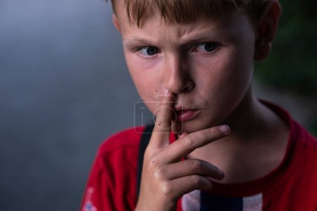 Téléchargez les photos : Portrait d'un garçon qui se piquait le nez. Garçon réfléchi sillonne ses sourcils. - en image libre de droit
