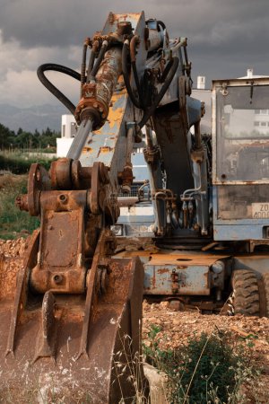 Photo for An old rusty blue excavator stands on a construction site. The rusty bucket of an old excavator is lowered to the ground. - Royalty Free Image