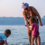 Grandmother and grandchildren on the sea beach. Grandmother plays with her granddaughter in the sea water of the Adriatic Sea.