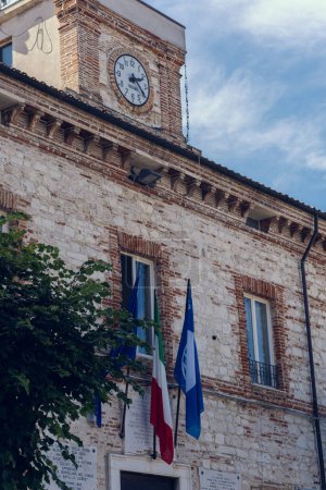 Numana Italy - 19 Sep 2023: Municipality Of Numana. Building of Municipality with clock and flags of: Italy, EU. Numana city. Summer sunny day.