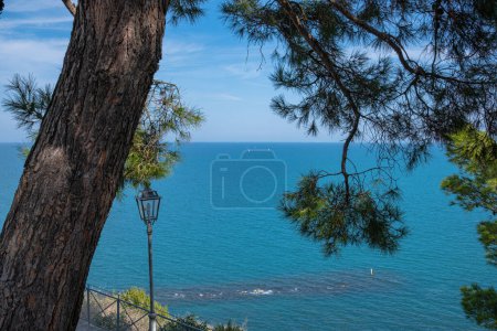 Strand der zwei Schwestern in Italien, Numana. Schöne Aussicht auf den beliebten Meeresstrand. Kiefern und andere Vegetation am Ufer und blaues Wasser, und über dem Meer gibt es einen blauen Himmel. Sommer sonniger Tag, Strand am Meer.