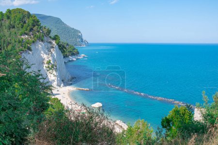 Strand der zwei Schwestern in Italien, Numana. Schöne Aussicht auf den beliebten Meeresstrand. Kiefern und andere Vegetation am Ufer und blaues Wasser, und über dem Meer gibt es einen blauen Himmel. Sommer sonniger Tag, Strand am Meer.