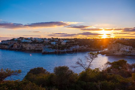 Beautiful panoramic view of Santanyi, Mallorca, Spain at golden hour of sunset. A town in the rays of the setting sun, beautiful sky and calm sea. Natural shot.