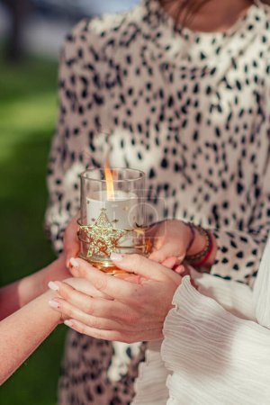 Three women are holding a glass glass with candles in their hands. Women's meeting, practice, esotericism. Burning candle in female hands.