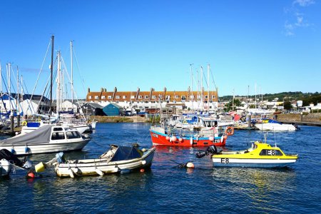 Foto de AXMOUTH, Reino Unido - 30 de agosto de 2022 - Barcos de pesca y yates amarrados a lo largo del río Axe en el puerto con edificios urbanos y Seaton en la parte trasera, Axmouth, Devon, Reino Unido, Europa, 30 de agosto de 2022. - Imagen libre de derechos