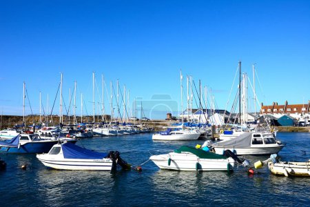 Foto de AXMOUTH, Reino Unido - 30 de agosto de 2022 - Barcos de pesca y yates amarrados a lo largo del río Axe en el puerto con edificios urbanos y Seaton en la parte trasera, Axmouth, Devon, Reino Unido, Europa, 30 de agosto de 2022. - Imagen libre de derechos