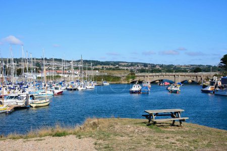 Foto de AXMOUTH, Reino Unido - 30 de agosto de 2022 - Puente sobre el río Axe con pequeños barcos pesqueros y yates amarrados en el puerto, Axmouth, Devon, Reino Unido, Europa, 30 de agosto de 2022. - Imagen libre de derechos