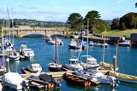 Foto de AXMOUTH, Reino Unido - 30 de agosto de 2022 - Puente sobre el hacha del río con pequeños barcos de pesca y yates en primer plano y la campiña de Devon en la parte trasera, Axmouth, Devon, Reino Unido, Europa, 30 de agosto de 2022. - Imagen libre de derechos