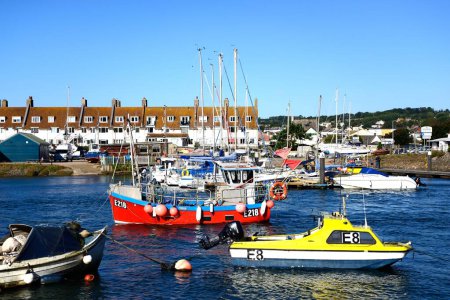 AXMOUTH, UK - AUGUST 30, 2022 - Fishing boats and yachts moored along the River Axe in the harbour with town buildings and Seaton to the rear, Axmouth, Devon, UK, Europe, August 30, 2022.