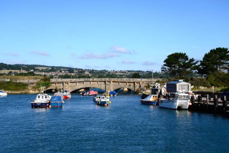 Foto de AXMOUTH, Reino Unido - 30 de agosto de 2022 - Puente sobre el hacha del río con pequeños barcos de pesca en primer plano y la campiña de Devon en la parte trasera, Axmouth, Devon, Reino Unido, Europa, 30 de agosto de 2022. - Imagen libre de derechos