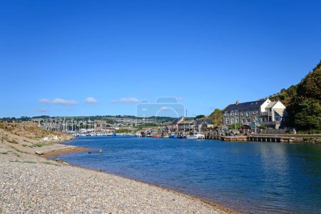 Foto de AXMOUTH, Reino Unido - 30 de agosto de 2022 - Barcos de pesca y yates amarrados a lo largo del río Axe en el puerto con edificios y campos en la parte trasera, Axmouth, Devon, Reino Unido, Europa, 30 de agosto de 2022. - Imagen libre de derechos