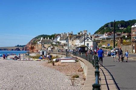 Photo for SIDMOUTH, UK - AUGUST 08, 2022 - Tourists relaxing on the beach and promenade with hotels overlooking the sea, Sidmouth, Devon, UK, Europe, August 08, 2022. - Royalty Free Image