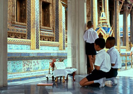 Foto de BANGKOK, TAILANDIA - 22 de octubre de 1991 - Niños rezando en el Complejo Wat Phra Kaew, Gran Palacio, Bangkok, Tailandia, 22 de octubre de 1991 - Imagen libre de derechos