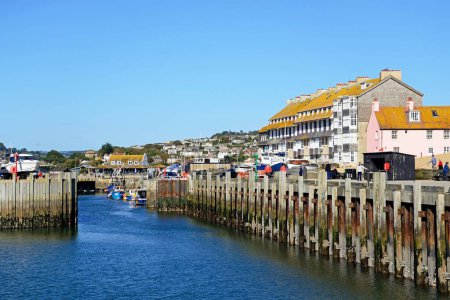 Foto de WEST BAY, Reino Unido - 10 de octubre de 2022 - Barco que entra en el puerto con la compuerta y los edificios de la ciudad en la parte trasera, West Bay, Dorset, Reino Unido, Europa, 10 de octubre de 2022. - Imagen libre de derechos