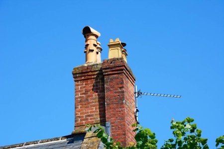 Chimeneas tradicionales de ladrillo rojo en lo alto de un edificio a lo largo de High Street, Chard, Somerset, Reino Unido, Europa