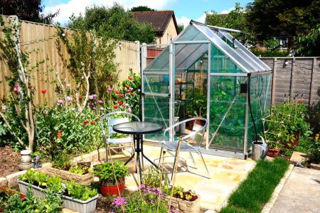 New modern polycarbonate hybrid greenhouse with a table and chairs in the foreground, Chard, Somerset, UK, Europe