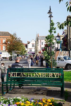 Téléchargez les photos : GLASTONBURY, Royaume-Uni - 05 septembre 2023- Homme assis sur un banc de fer le long de la rue Magdalene avec des magasins du centre-ville à l'arrière, Glastonbury, Somerset, Royaume-Uni, Europe, 05 septembre 2023. - en image libre de droit