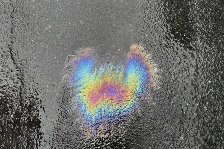Color image of fuel oil spilled on asphalt. Rainbow colors of oil residue on water.