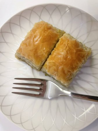 Saveur traditionnelle de dessert turque.Baklava.Baklava. Deux tranches de baklava et une fourchette sur une assiette blanche.