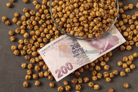 Photo for Close-up of a plate full of Turkish roasted chickpeas and 200 Turkish liras next to it, implying that the prices of roasted chickpeas are increasing. - Royalty Free Image