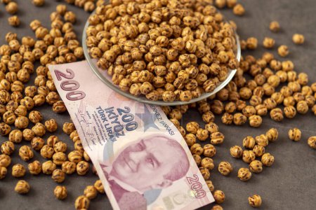 Photo for Close-up of a plate full of Turkish roasted chickpeas and 200 Turkish liras next to it, implying that the prices of roasted chickpeas are increasing. - Royalty Free Image