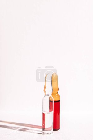 Photo for Injections of B vitamins. Ampoules with red liquid on a white background. Beauty and health concept. copy space. Blur and selective focus. vertical photo - Royalty Free Image
