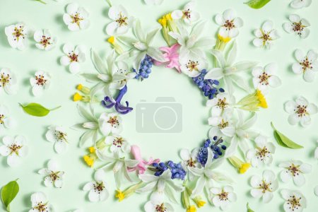 Flat lay frame from spring flowers on a light green background. View from above, copy space. Beautiful floral pattern in pastel colors. 