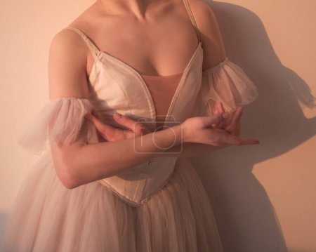 Photo for Beautiful ballerina poses in a studio in a beautiful dress with a decollete. Hands perform ballet movements. photo shows the beauty of classical ballet. - Royalty Free Image