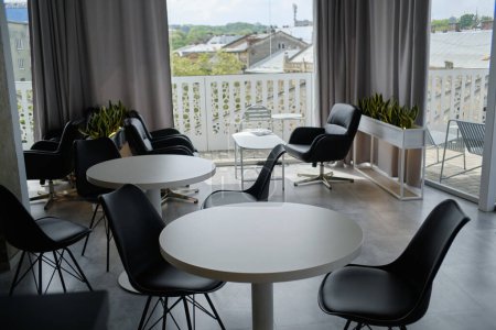 Innenraum eines gemütlichen Cafés mit Sommerterrasse. Schwarz-weiße Möbel. Gemütliche Café-Atmosphäre 