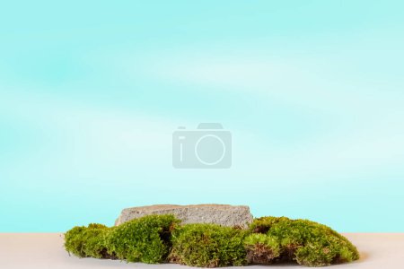Natural style. Stone podium with green moss on a gradient soft blue background. Still life for the presentation of cosmetic products. Copy space