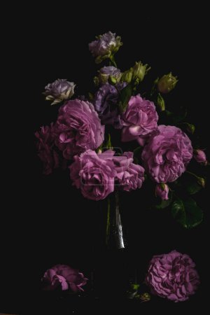 Stillleben. Luxus-Strauß Rosen und Lisianthus in einer Glasvase auf schwarzem Hintergrund. Stimmungsvolle Blumen. Farbblüte.
