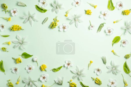 Flat lay frame from spring flowers on a light green background. View from above, copy space. Beautiful floral frame.
