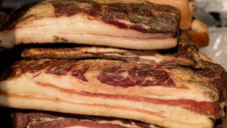 Large pieces of smoked lard with meat close-up on a market counter. 