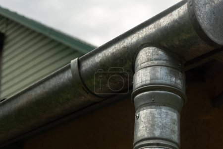 Téléchargez les photos : Gouttière d'eau de pluie sous le toit de la maison. Architecture de récolte de l'eau de pluie. Concentration floue et sélective - en image libre de droit