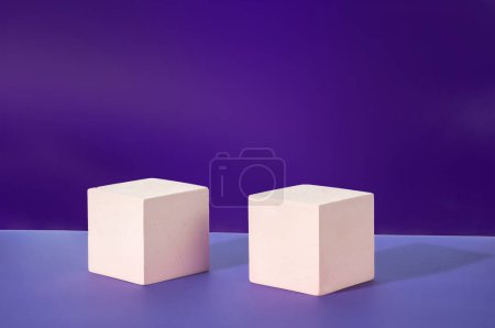Zwei weiße Zementwürfel auf violettem Hintergrund. Mockup für die Vorführung kosmetischer Produkte. Kopierraum