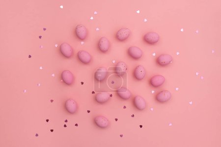 Foto de Feliz tarjeta de Pascua. Los huevos de chocolate rosa brillante se encuentran sobre un fondo rosa pastel. Corazones brillantes y brillantes. Composición minimalista. Uso en materiales de marketing, elemento decorativo en diversos contextos - Imagen libre de derechos