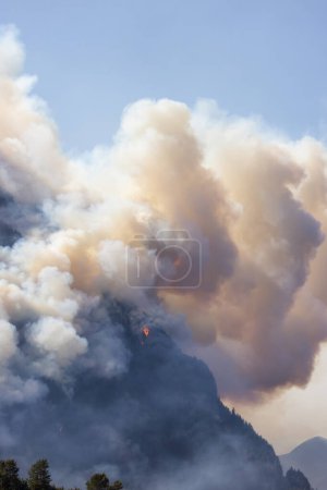 Foto de BC Forest Fire y Smoke sobre la montaña cerca de Hope durante un caluroso día soleado de verano. Columbia Británica, Canadá. Incendio forestal desastre natural - Imagen libre de derechos