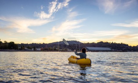 Femme aventureuse faisant du kayak sur un kayak gonflable dans l'océan Pacifique. Sunset Sky. Port Moody, Vancouver, Colombie-Britannique, Canada. Aventure Sport Voyage
