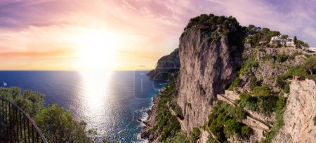 Foto de Rocky Coast by Sea at Touristic Town on Capri Island in Bay of Naples, Italy (en inglés). Sunset Sky Art Render. Panorama - Imagen libre de derechos