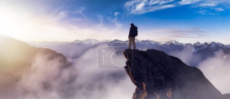 Téléchargez les photos : Adventurous Man Hiker standing on top of peak with rocky mountain in background. Adventure Composite. 3d Rendering rocks. Aerial Image of landscape from BC, Canada. Sunset Sky - en image libre de droit